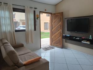 a living room with a couch and a flat screen tv at Casa de Praia Martins De Sá Condomínio Caraguatatuba in Caraguatatuba