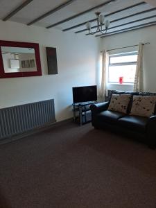 a living room with a couch and a television at Bank Top Farm Cottages in Stoke on Trent