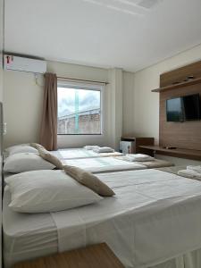 eine Reihe weißer Betten in einem Zimmer mit Fenster in der Unterkunft Hotel Carvalho in Ibiapina