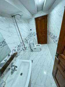 Baño blanco con lavabo y aseo en Decent Lodge Guest House F-10 en Islamabad