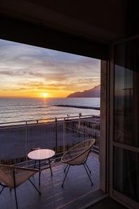 een balkon met een tafel en stoelen en uitzicht op de oceaan bij Cas’ A Mare - Beachfront Luxury Suites in Salerno