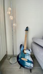 uma guitarra azul sentada no chão ao lado de um sofá em Maison chic avec Jacuzzi & Jardin Paisible em Chauray