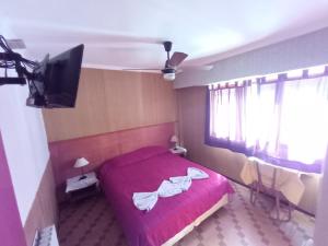 um quarto com uma cama vermelha e uma televisão de ecrã plano em Nuevo Hotel Tivoli em Mar del Plata
