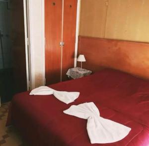 Una cama roja con dos toallas blancas. en Nuevo Hotel Tivoli en Mar del Plata