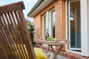 eine Holzbank auf einer Veranda mit einer Flasche Wein in der Unterkunft Ferienwohnung „Langer Jammer“ im Hesterhoff in Bad Zwischenahn
