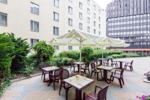 un patio al aire libre con mesas, sillas y una sombrilla en Ibis Praha Wenceslas Square, en Praga