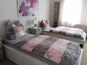 two beds in a bedroom with pink and grey at Ferienhaus Lindenhof 