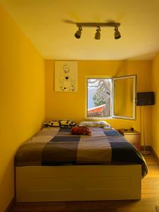 um quarto com uma cama com paredes amarelas e uma janela em La casa di Judy e Frank em Tarquinia