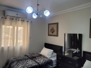 a bedroom with a bed and a dresser and a chandelier at Logistic Apartment in Cairo
