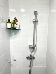 prysznic z wężem w wyłożonej białymi kafelkami łazience w obiekcie I'm house w Seulu