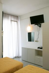 una camera con due letti e una televisione a muro di Hotel Hollywood a Rimini