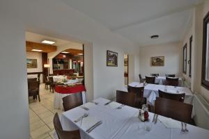 a restaurant with white tables and chairs and a dining room at Guesthouse Babin Zub in Crni Vrh