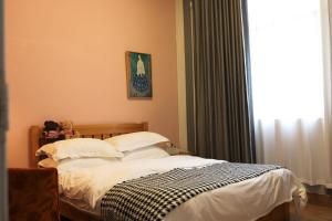 a bedroom with a bed with white sheets and a window at Changsha Fuxiangyuan International Hostel in Changsha
