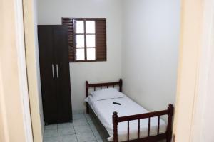 a small bedroom with a bed and a window at Hotel Gringos in Londrina