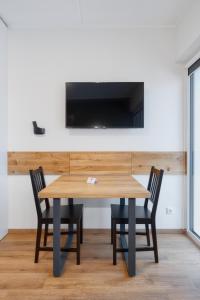 mesa de madera con 2 sillas y TV en la pared en TopFloor Apartments en Vilna