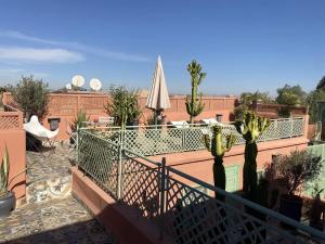 een balkon met een patio met een parasol en een cactus bij Ryad El Borj in Marrakesh