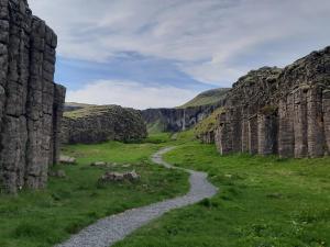 un camino sinuoso entre dos paredes de piedra en un campo verde en Stracta Apartments, en Kirkjubæjarklaustur