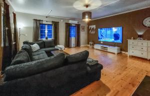 ein Wohnzimmer mit einem schwarzen Sofa und einem Flachbild-TV in der Unterkunft Cozy Home In Skepplanda With Private Swimming Pool, Can Be Inside Or Outside in Skepplanda