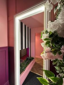 a mirror in a pink room with white flowers at Copper and Blossom in Manchester
