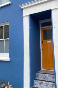 un edificio azul con una puerta naranja y escaleras en Hendon Street Beach Huts en Brighton & Hove