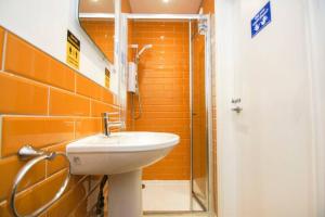 y baño de color naranja con lavabo y ducha. en Hendon Street Beach Huts en Brighton & Hove
