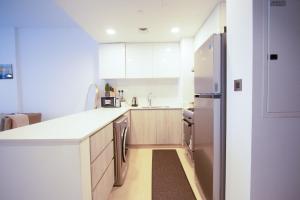 a kitchen with white cabinets and a stainless steel refrigerator at We are 25 Mins to Downtown Dubai in Ḩiz̧āyib az Zānah