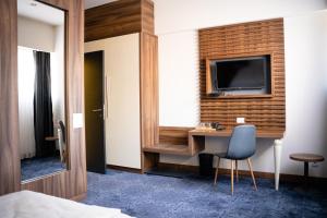 a bedroom with a desk and a tv on a wall at Olivia Rooms in Belgrade