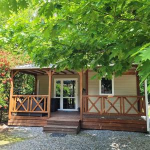 una pequeña casa con un gran porche de madera y una puerta en Mobil Home Confort en Lescar