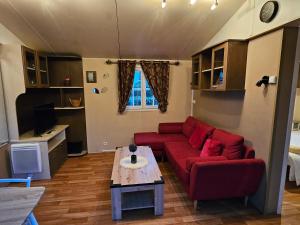 sala de estar con sofá rojo y mesa en Mobil Home Confort, en Lescar