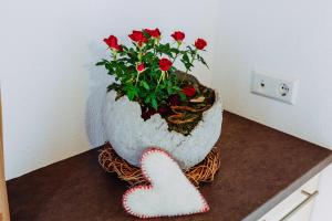 un vase avec une plante aux roses rouges et un cœur dans l'établissement Ausserglieshof Wohnung Weißkugel, à Malles Venosta