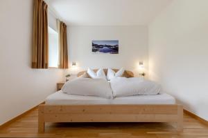 - une chambre blanche avec un lit et des oreillers blancs dans l'établissement Ausserglieshof Wohnung Weißkugel, à Malles Venosta