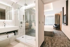 een badkamer met wastafel en douche en een bed bij Hotel International Brno in Brno