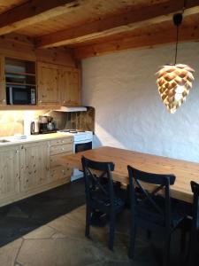uma cozinha com uma mesa de madeira e algumas cadeiras em Troll Fjordhytter em Syvde