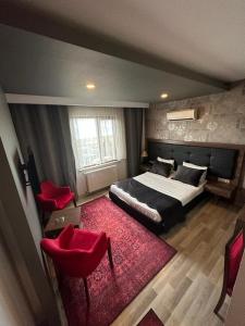 1 dormitorio con 1 cama y 2 sillas rojas en New Akçaabat Hotel, en Akcaabat