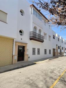 un edificio blanco al lado de una calle en alojamiento saturno1, en Conil de la Frontera