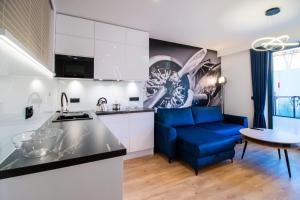 a kitchen and a living room with a blue couch at Apartament AVIATOR - lokalizacja w centrum, wysoki standard, balkon, prywatny parking in Nowy Targ