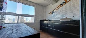 a kitchen with a counter and a large window at Apartamento Praia Grande -Canto do Forte in Praia Grande