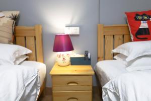 a bedroom with two beds and a lamp on a night stand at Changsha Fuxiangyuan International Hostel in Changsha