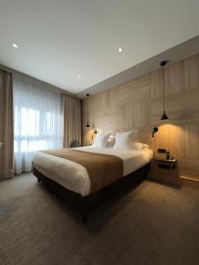 a bedroom with a large bed with a large window at LOGIS Hôtel Borel in Dunkerque