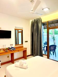 a hotel room with a bed and a television at Vilu Residence in Maamigili
