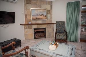 een woonkamer met een open haard en een televisie bij Bluewater Reservations in Port Elizabeth