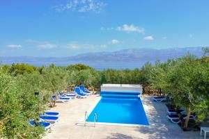 a swimming pool with lounge chairs and the ocean at Holiday Home Malačnica in Supetar