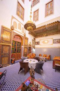 ein großes Zimmer mit Tischen, Stühlen und einem Kronleuchter in der Unterkunft Riad Hayat Fes in Fès