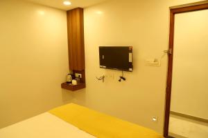 a room with a tv on a wall with a bed at Hotel Hinduja Empire in Surat