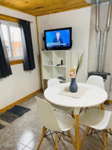 a white table and chairs in a room with a tv at Mirai Cabañas La Carmen in Veintiocho de Noviembre