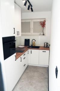 a kitchen with white cabinets and black appliances at apartament 1000-lecia in Wąbrzeźno