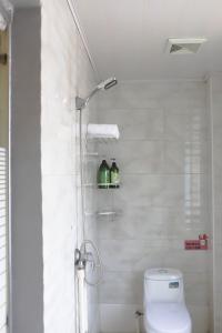 a bathroom with a toilet and a shower with two bottles at Changsha Fuxiangyuan International Hostel in Changsha