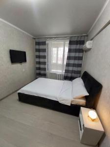 een kleine slaapkamer met een bed en een raam bij Отличная квартира со всеми удобствами. in Alma-Ata