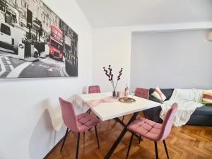 a dining room with a white table and pink chairs at Holiday Apartments PIATA ROMANA with Balcony in Bucharest