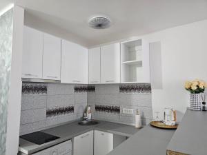 a white kitchen with white cabinets and a sink at Vio's Galati Apartment in Galaţi